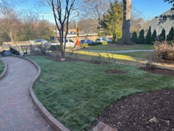 A brick walkway going through a lush green park