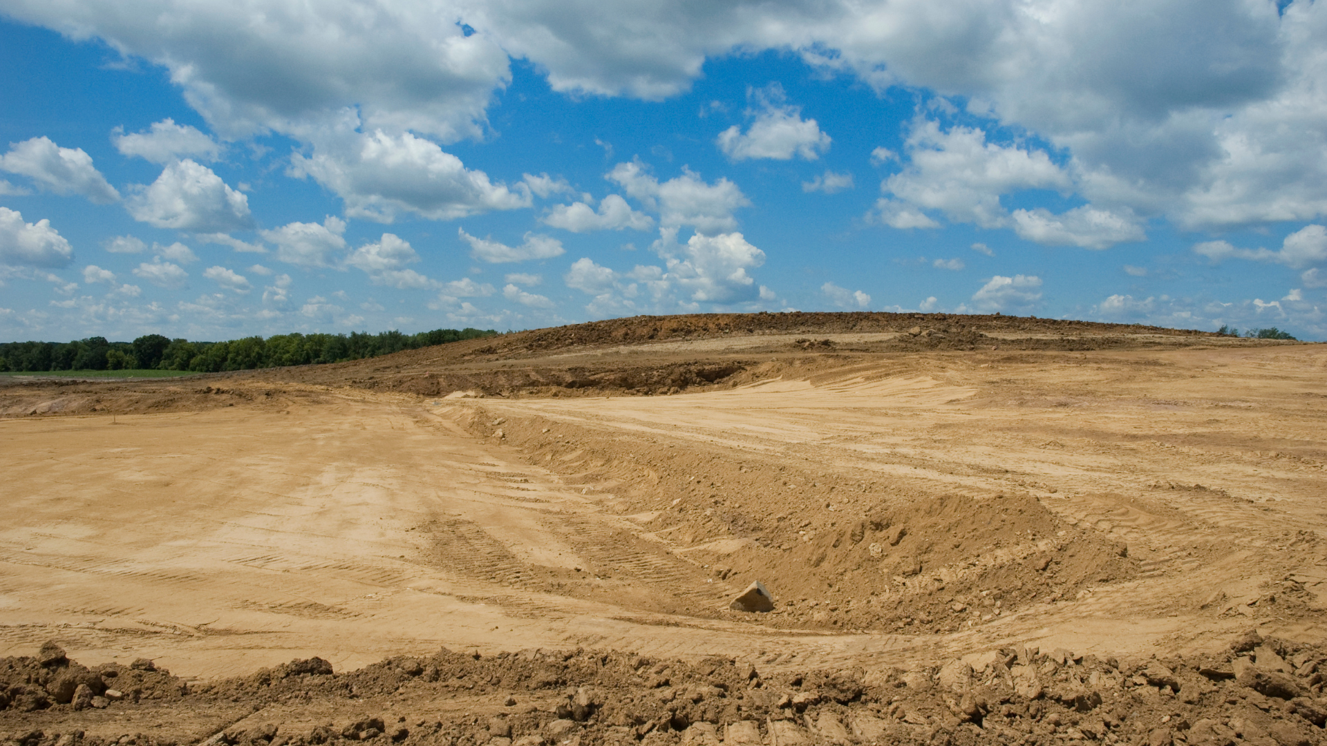 Two bulldozers are working on a dirt field.