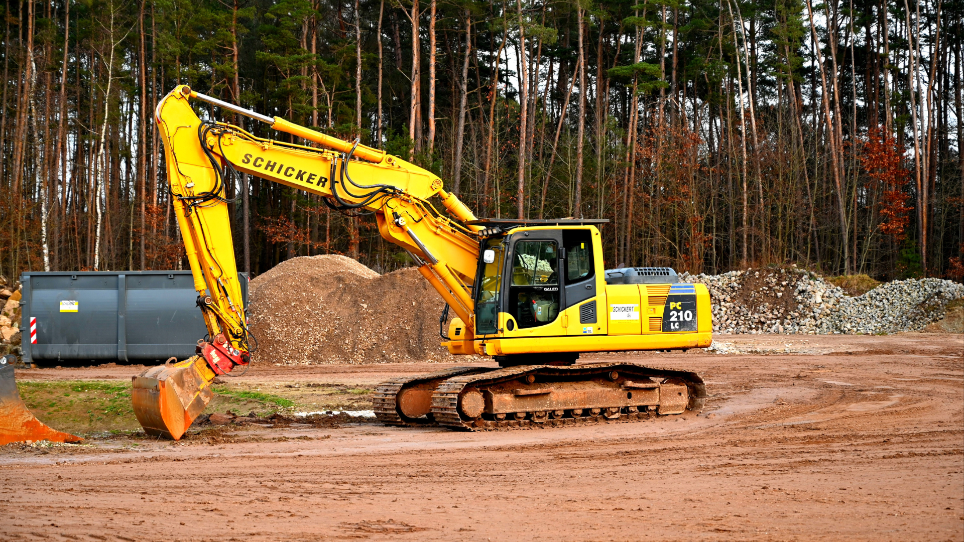 Two bulldozers are working on a dirt field.
