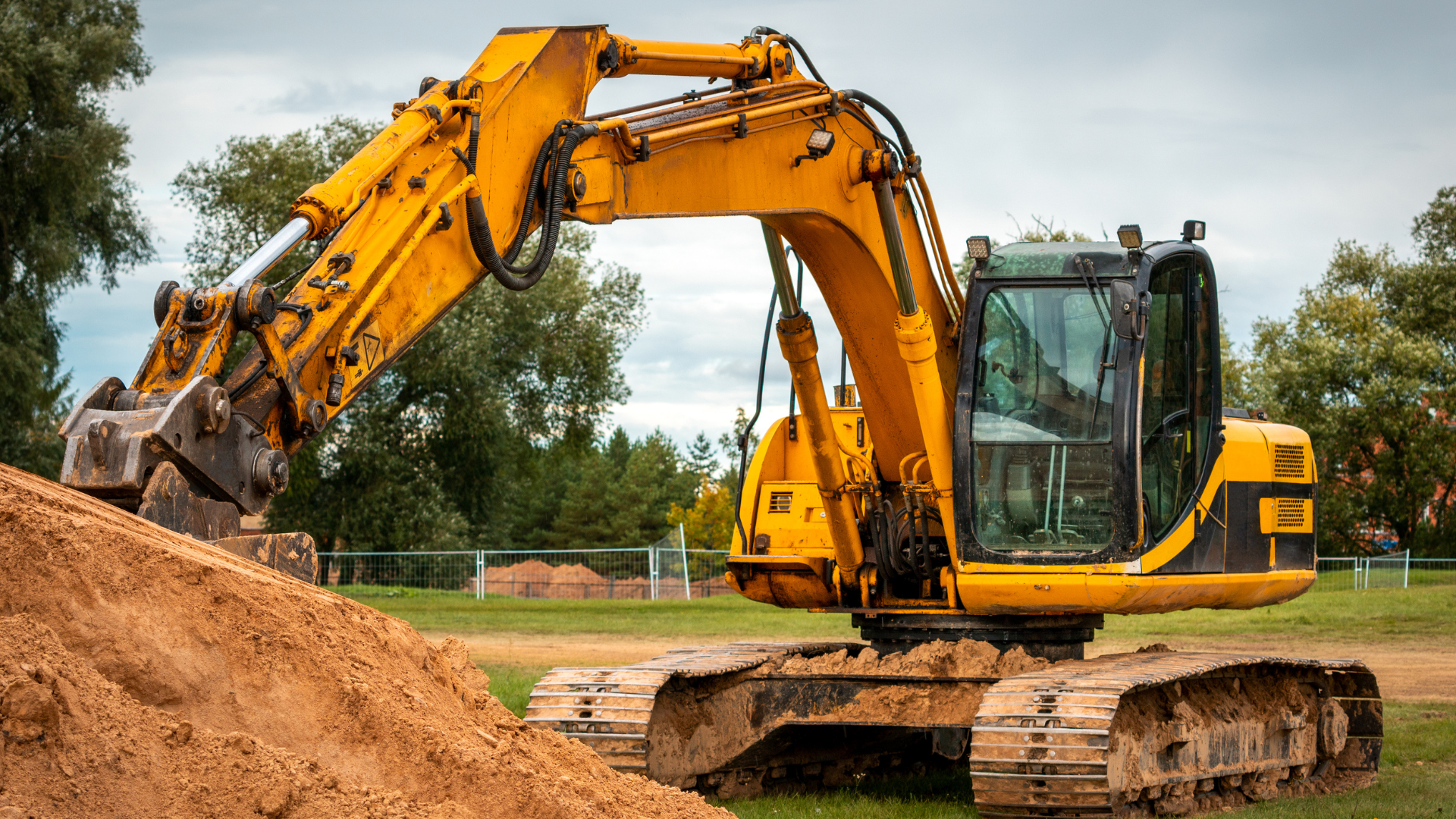 Two bulldozers are working on a dirt field.