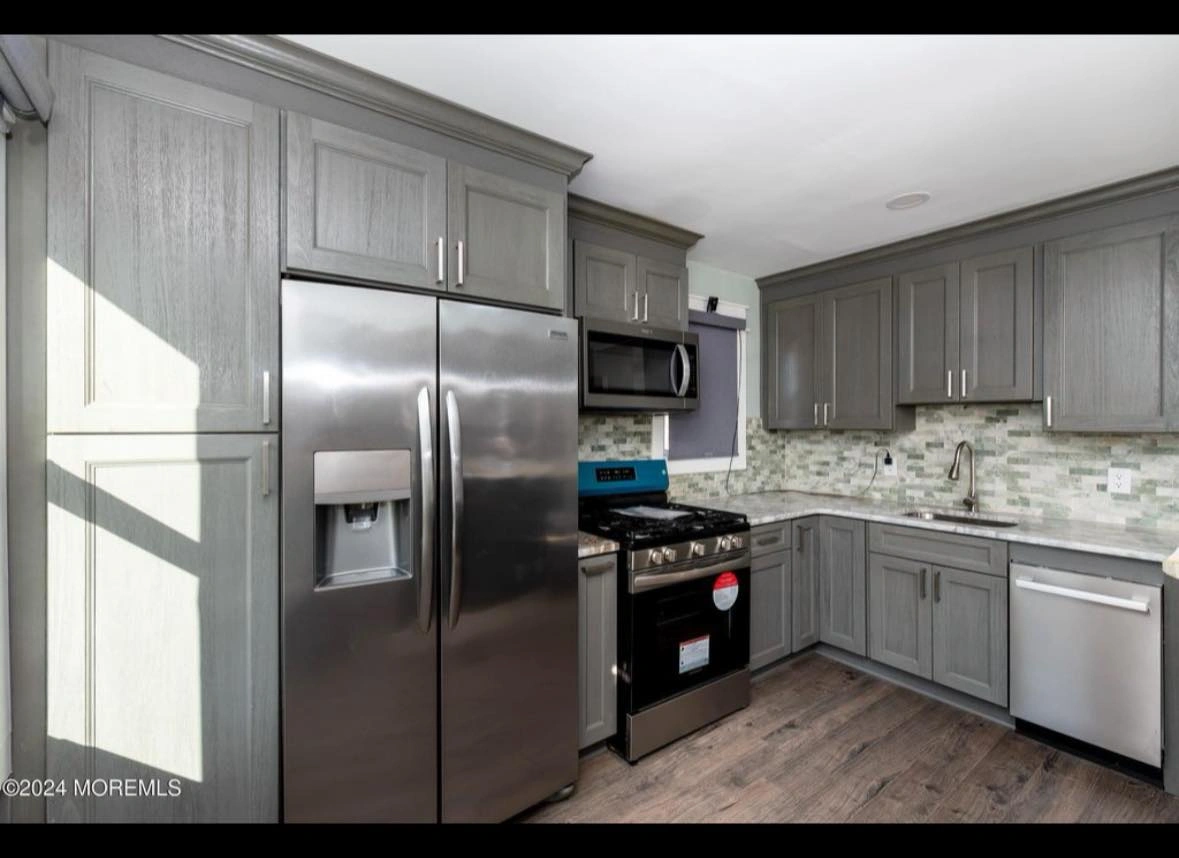 Gray kitchen with stainless steel appliances, cabinets, and light-colored countertops and floors.