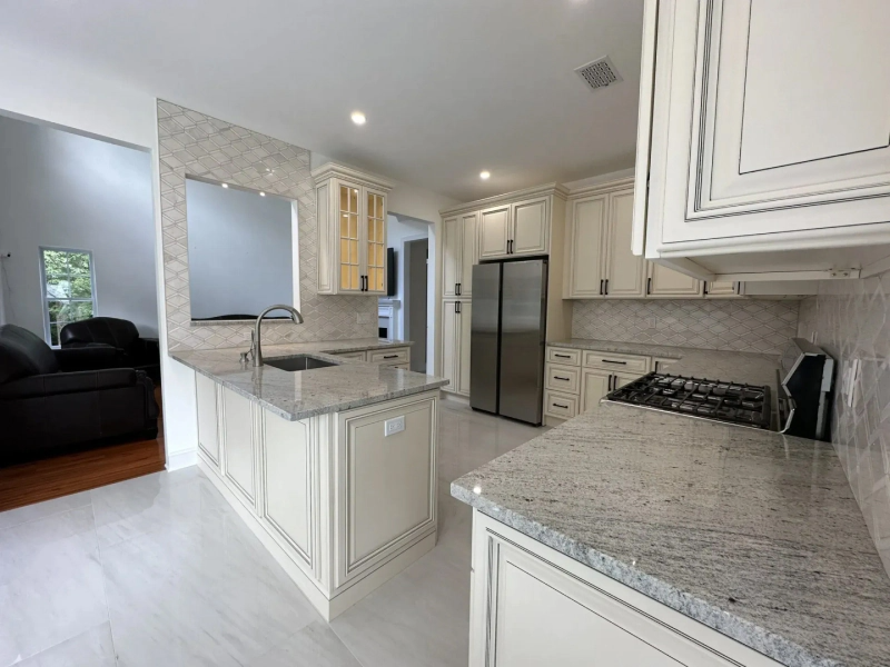 Newly renovated kitchen with white cabinets, light-colored granite countertops, and stainless steel appliances. The room has a bright, open feel.
