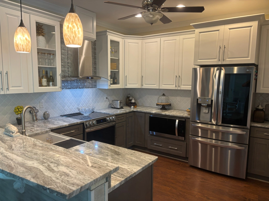 Modern kitchen with white and gray cabinets, stainless steel appliances, and granite countertops.