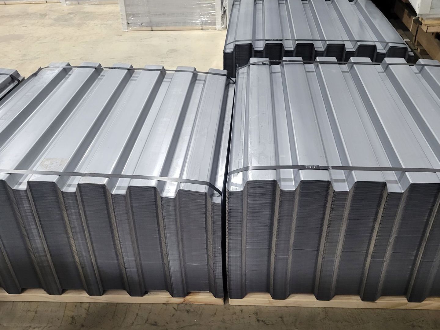 A stack of gray metal sheets on a wooden pallet