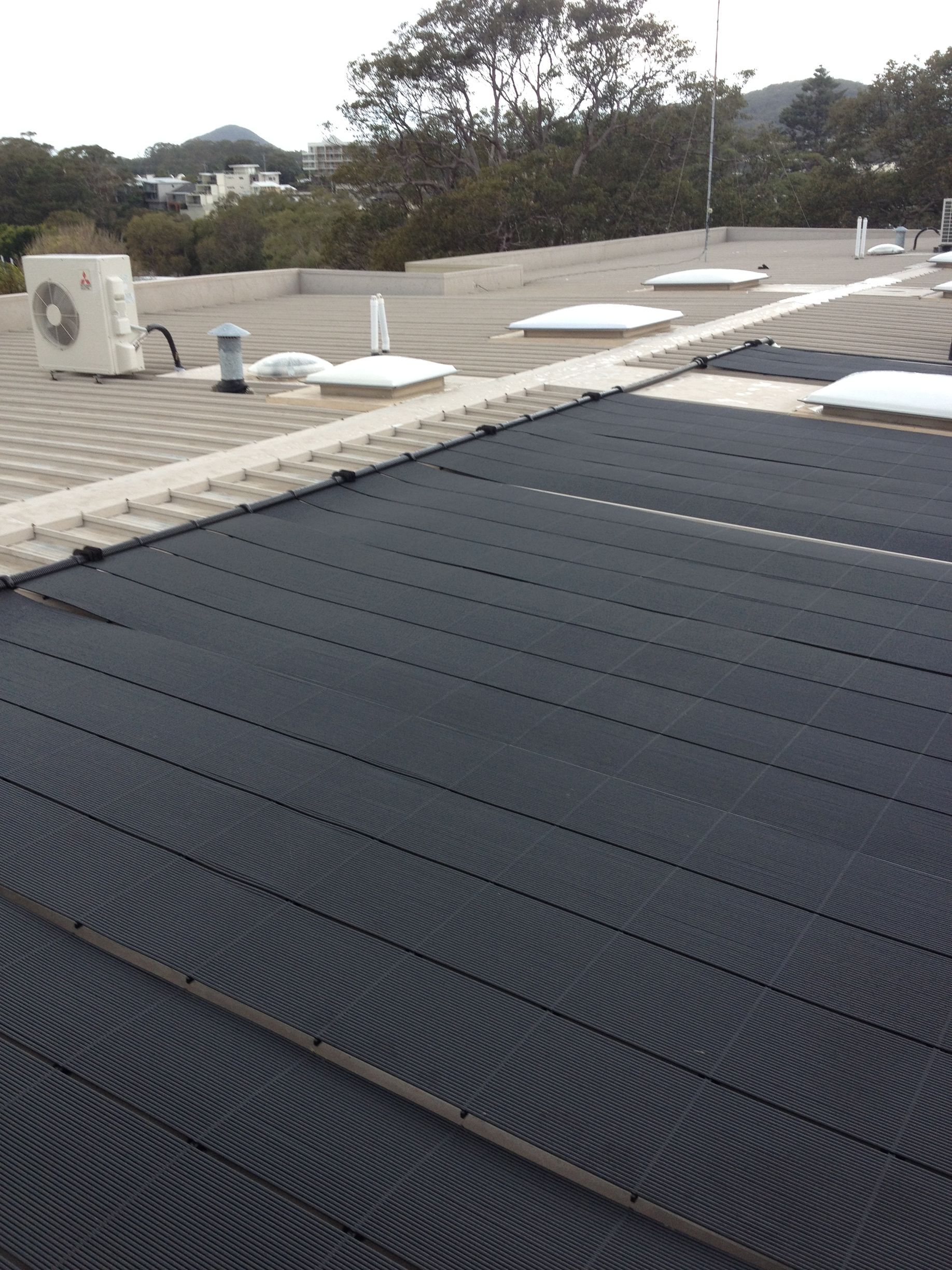 There is a Solar Panel on the Roof of a House — Newcastle Solar Pool Heating Systems In Maitland, NSW