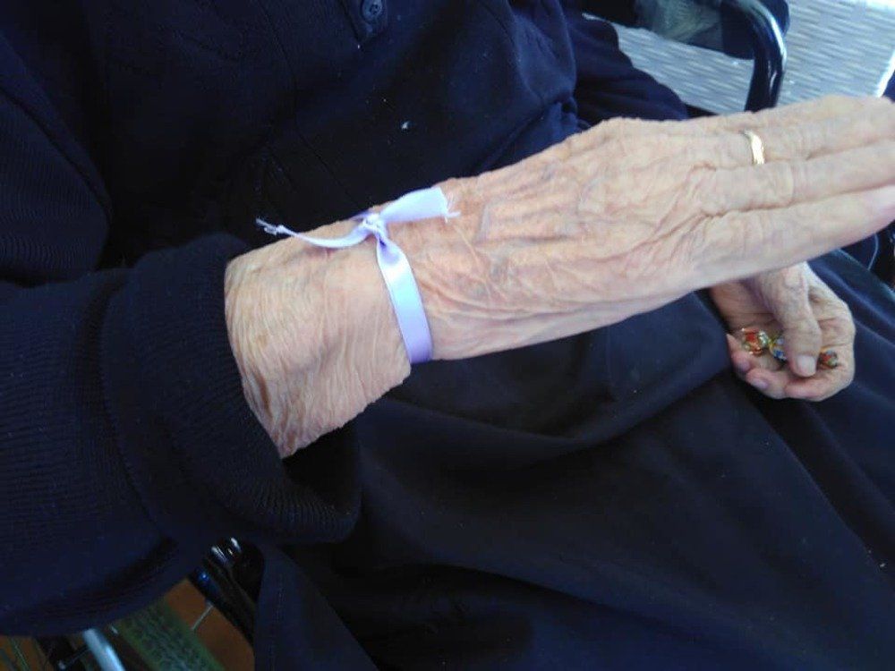 donna anziana con nastro in raso sul polso