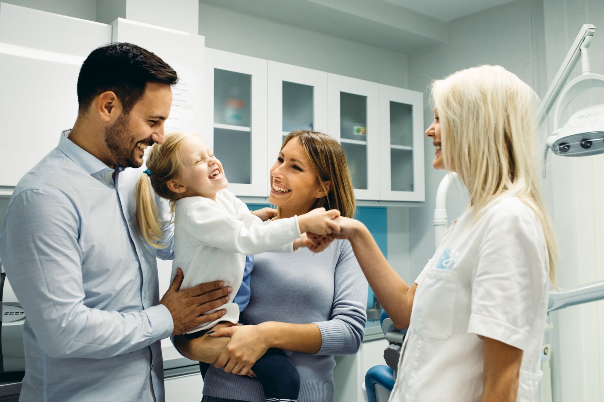A cheerful family in a dentist's office is greeting the dentist.