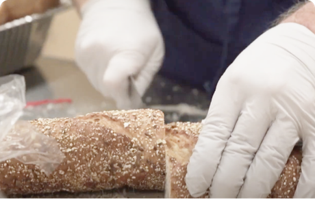close up of someone cutting bread wearing gloves