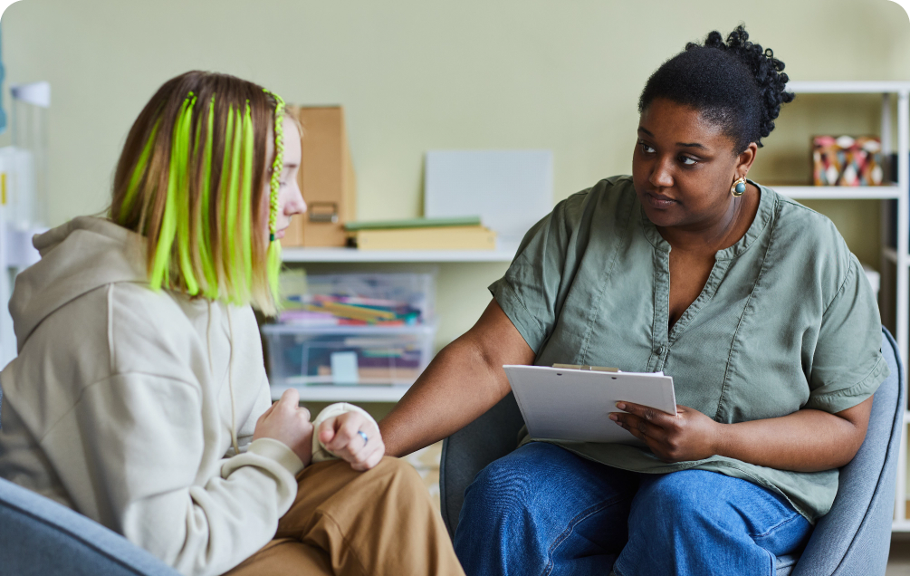 girl with green dyed hair talking with another woman wearing a gray shirt