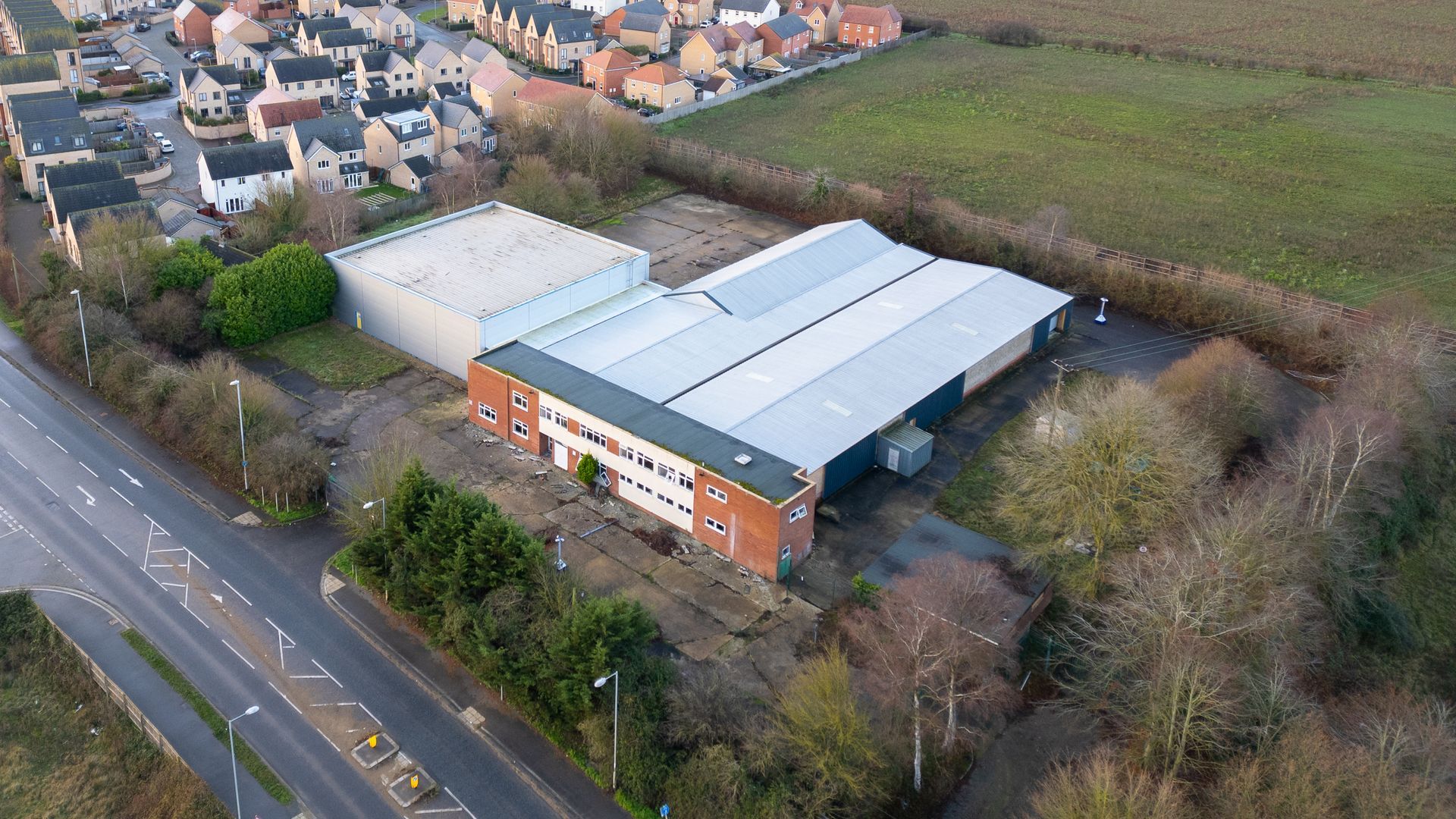 Drone aerial view of the former Pentair warehouse brownfield site on Station Road in Northstowe, Cambridgeshire, showing current site conditions.