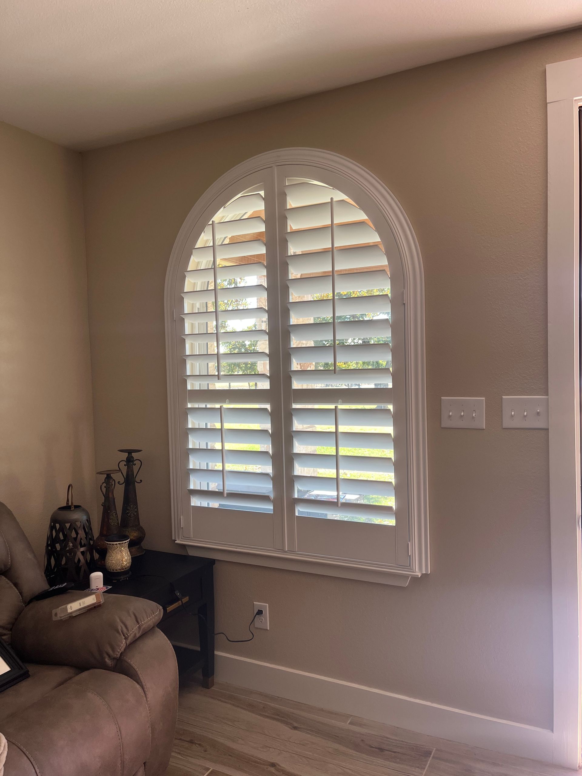 A living room with a couch and a window with shutters on it.
