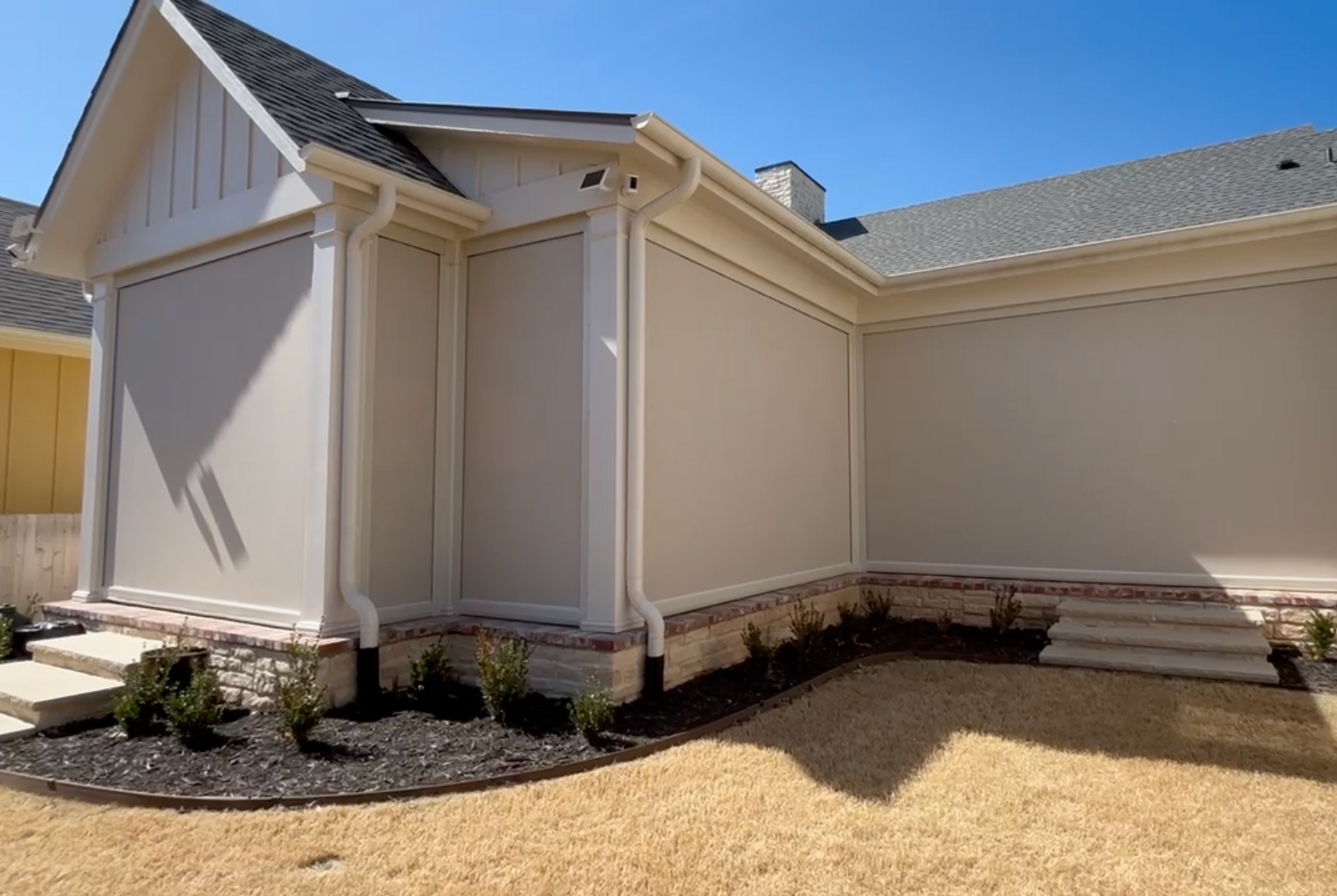 A white house with a gray roof and shutters on the windows.