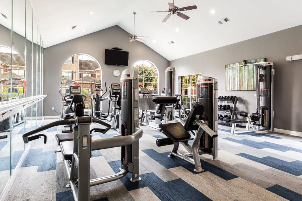 a large gym with a lot of equipment and a ceiling fan at Marquis on Park Row in Houston, TX.