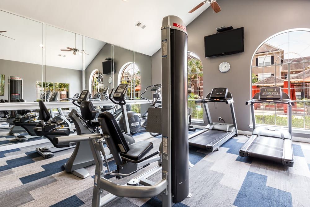 a gym with a lot of equipment and a television on the wall at Marquis on Park Row in Houston, TX.