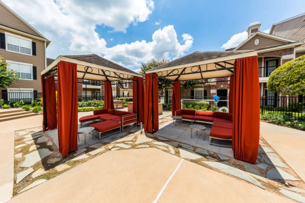 two gazebos with red curtains in front of a building at Marquis on Park Row in Houston, TX.