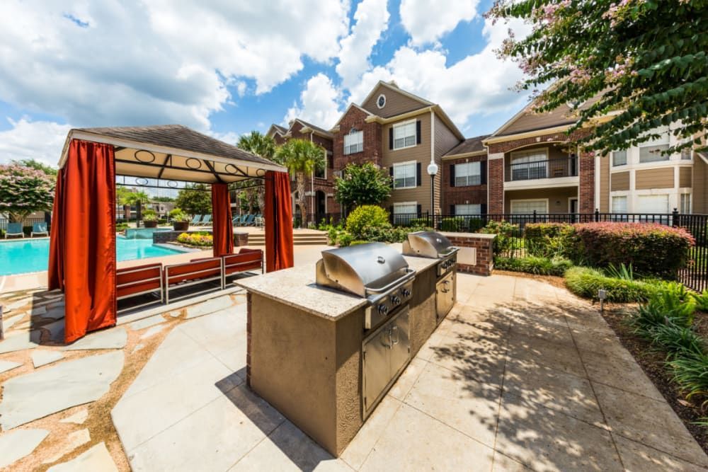a grill is sitting in front of a gazebo next to a pool at Marquis on Park Row in Houston, TX.