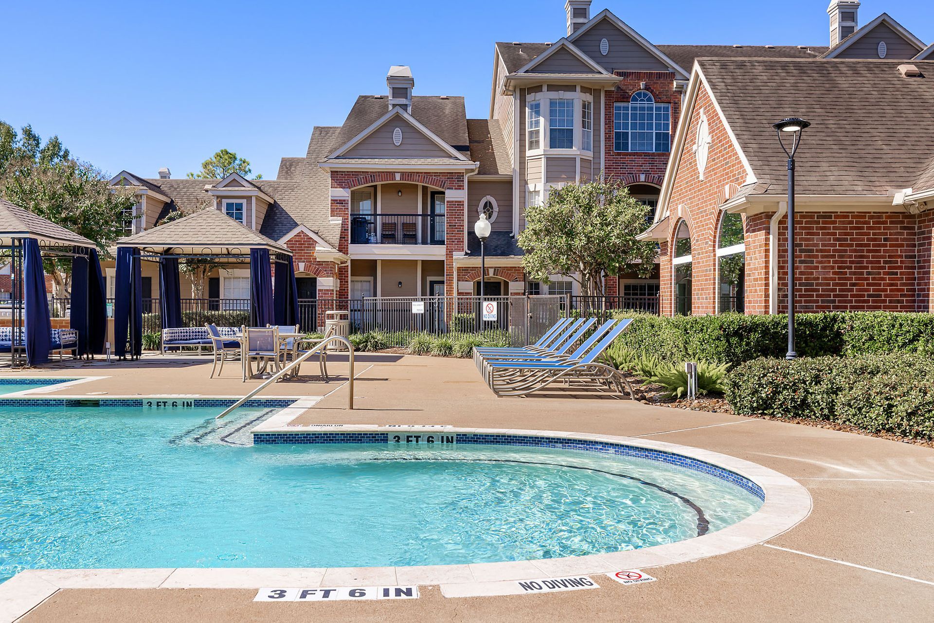 Outdoor pool area at an apartment community with lounge chairs and cabanas.