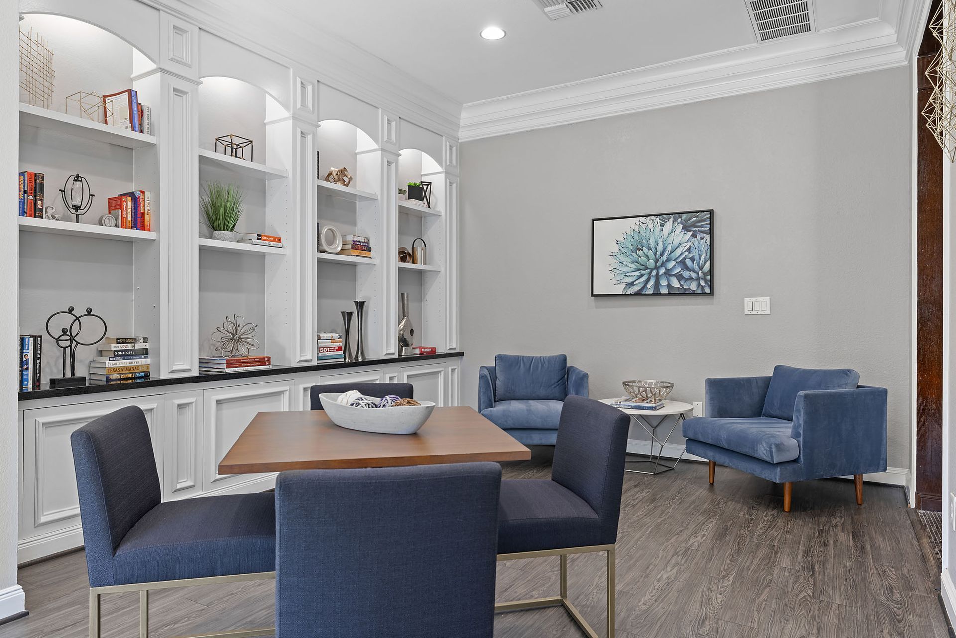 Lounge area with white built-in shelves, decor, and blue upholstered seating.