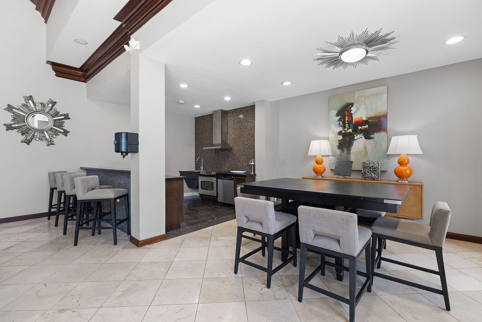 Communal lounge with a kitchenette, bar seating, and a large dining table.