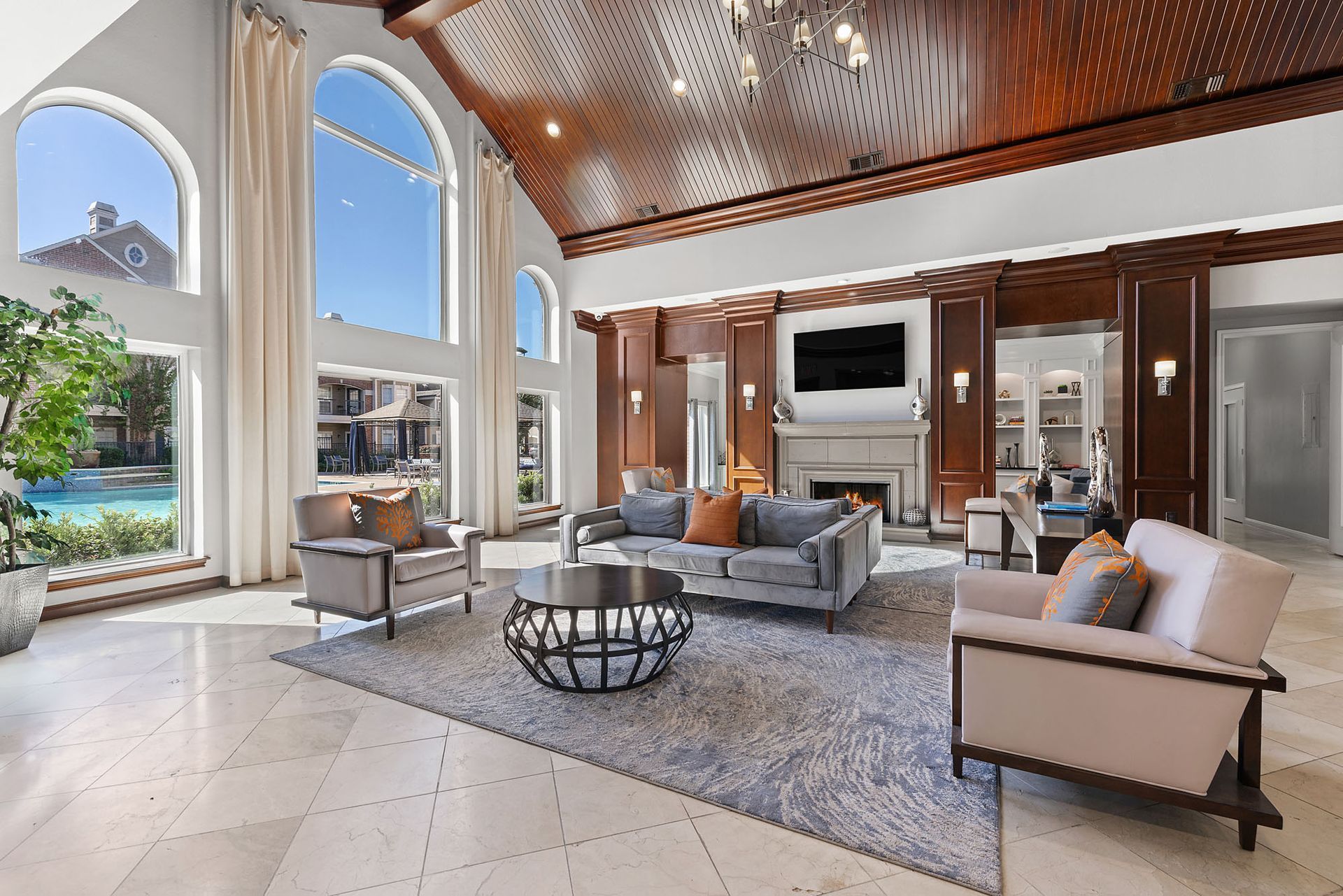 Luxurious resident lounge with arched windows, wood-paneled walls, and a fireplace.