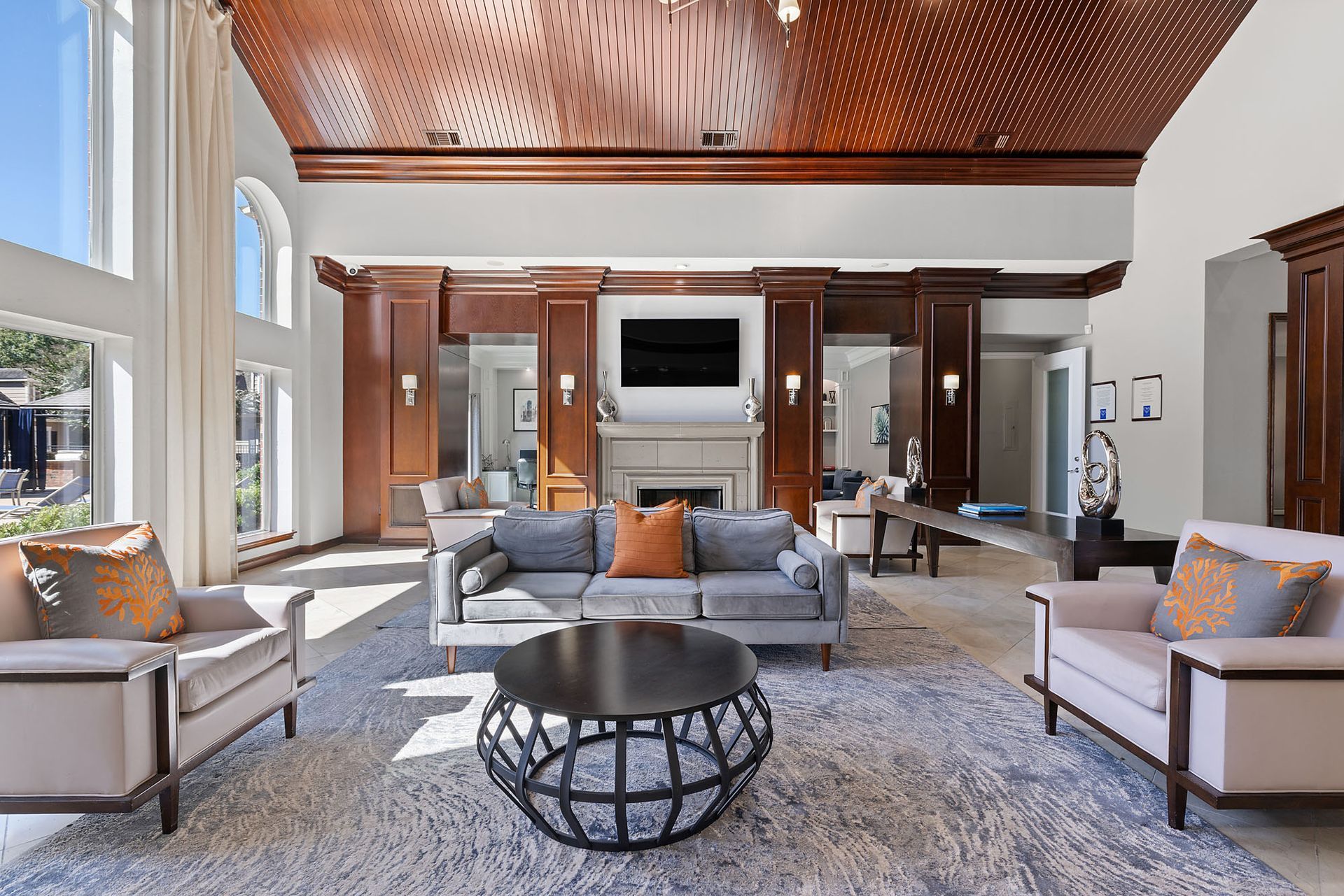Elegant apartment community lobby with wood-paneled ceiling, fireplace, and seating area.