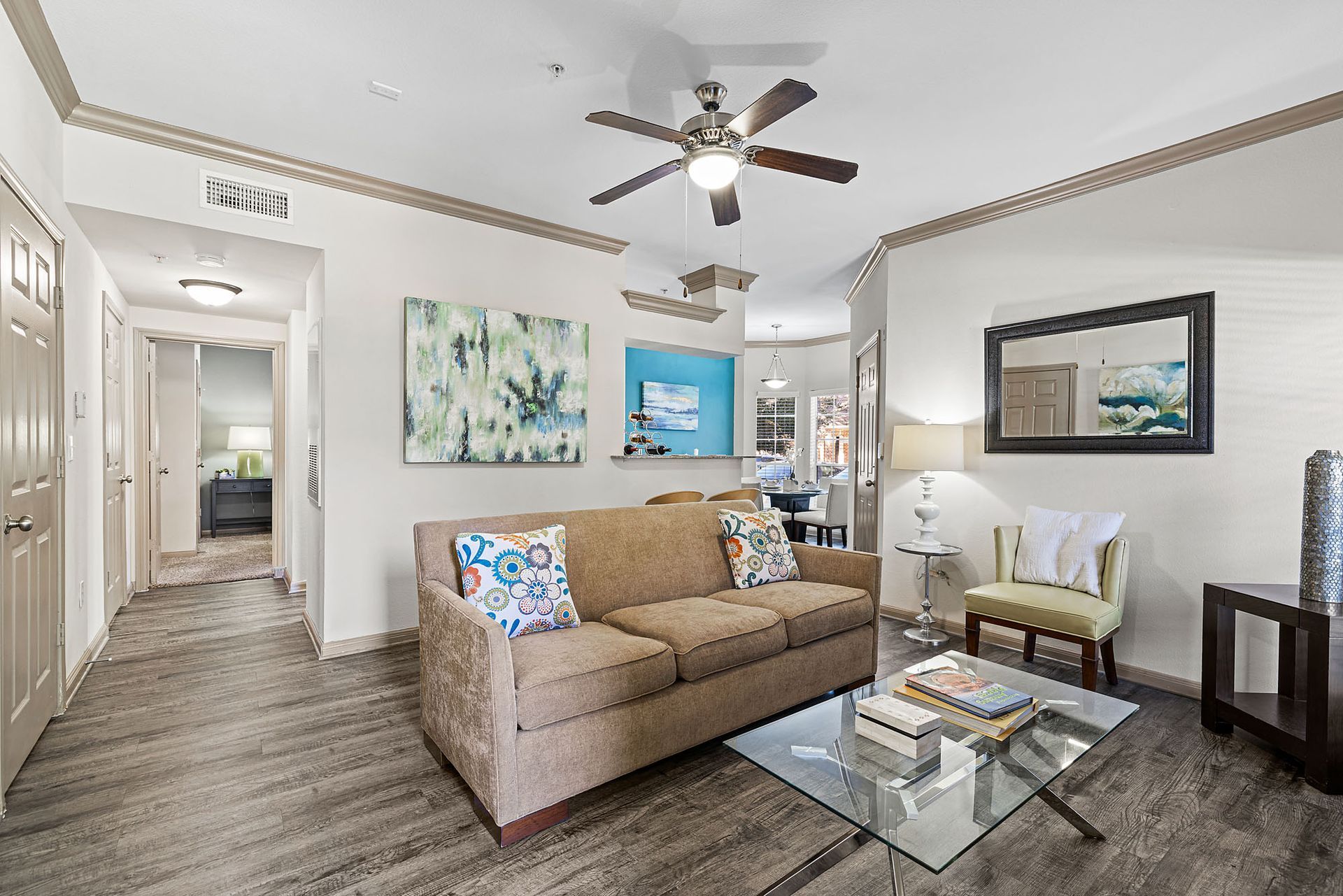 Living room in an apartment with a beige sofa, glass coffee table, and wall art.