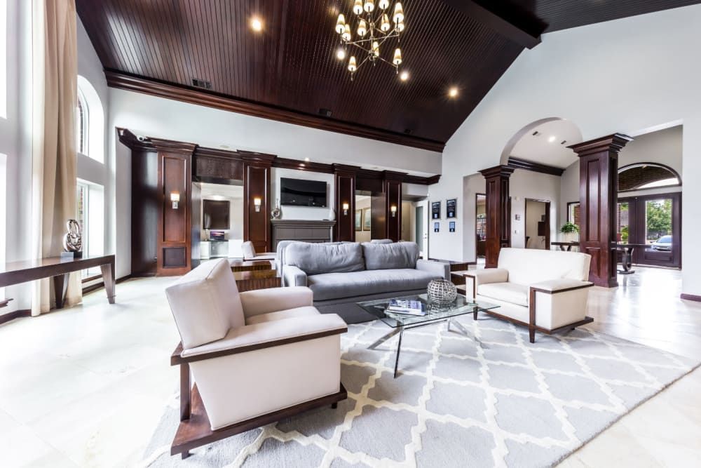 a living room with a couch, chairs, a coffee table, and a chandelier at Marquis on Park Row in Houston, TX.