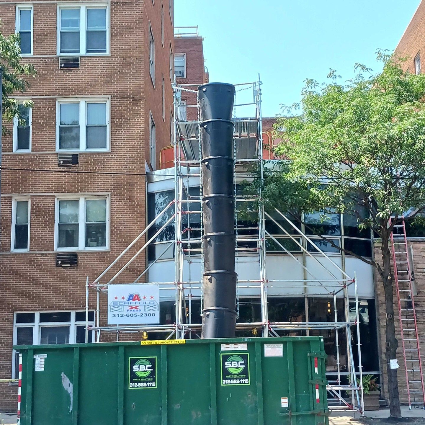 a brick building with a green dumpster in front of it