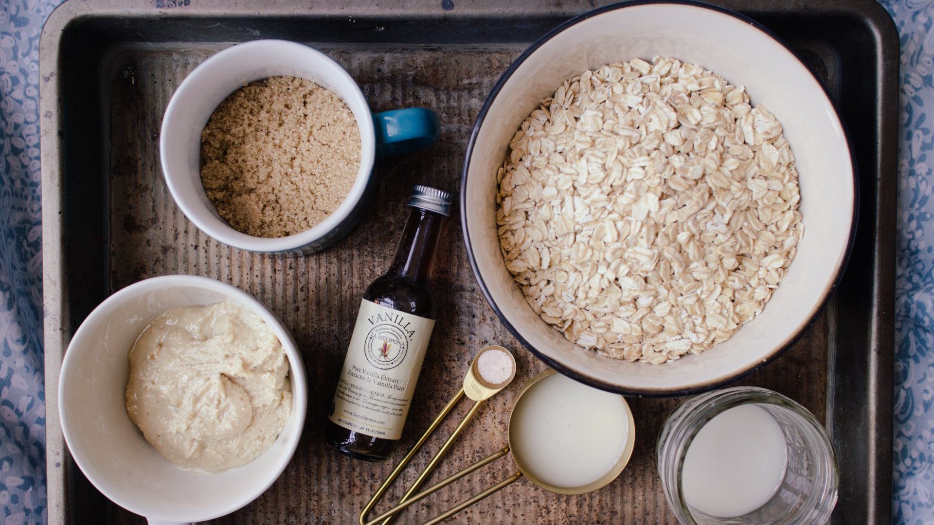 A tray filled with bowls of oats , flour , vanilla , and other ingredients.