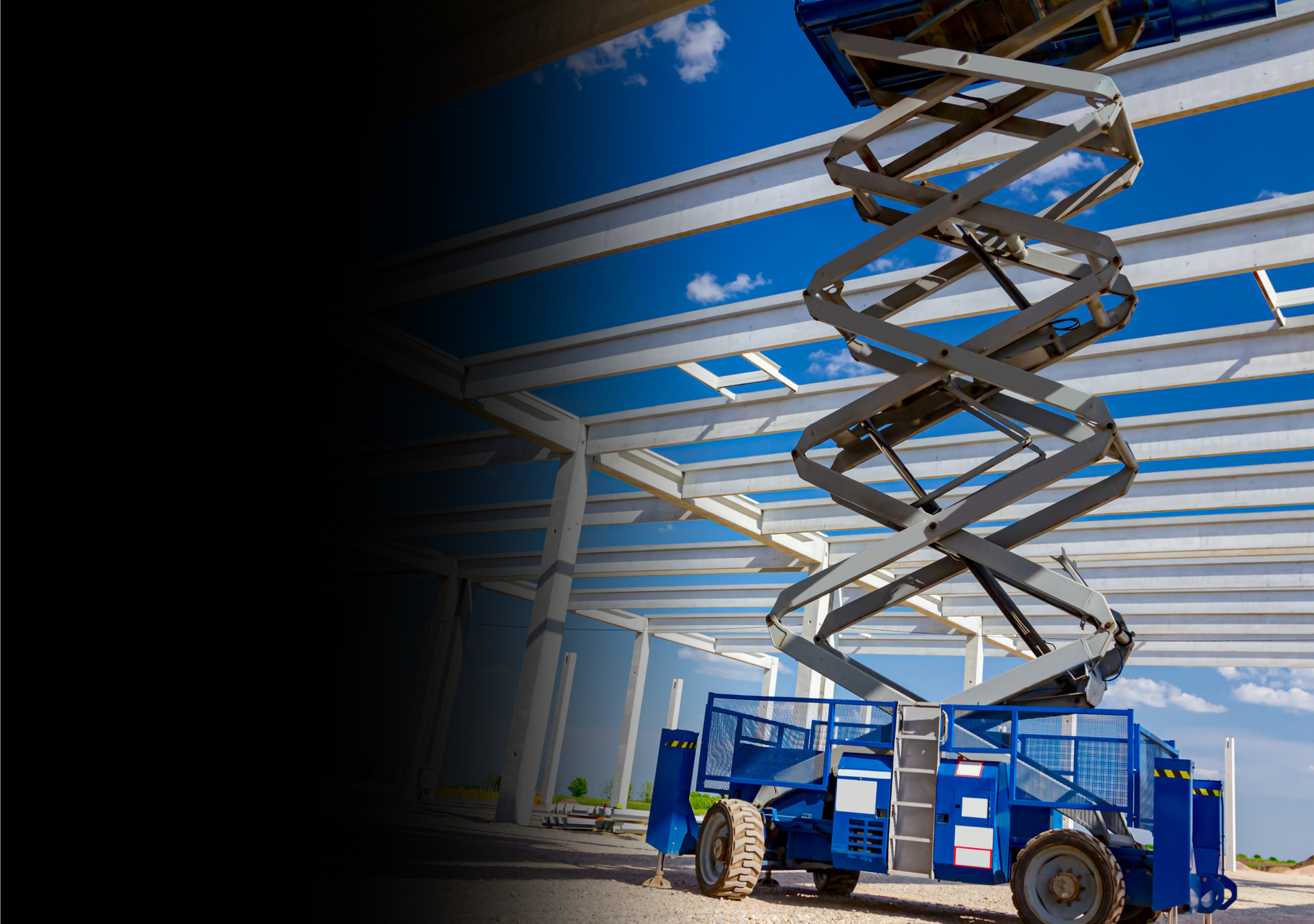 A blue scissor lift is sitting on top of a building under construction.