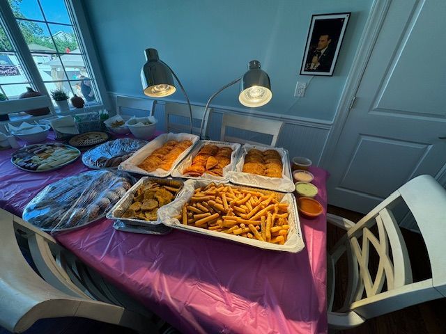 A table with a purple table cloth and a bunch of food on it