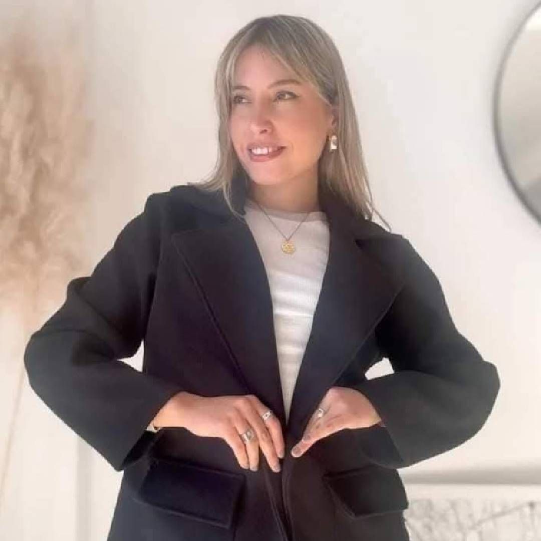 Una mujer lleva una chaqueta negra y una camisa blanca.