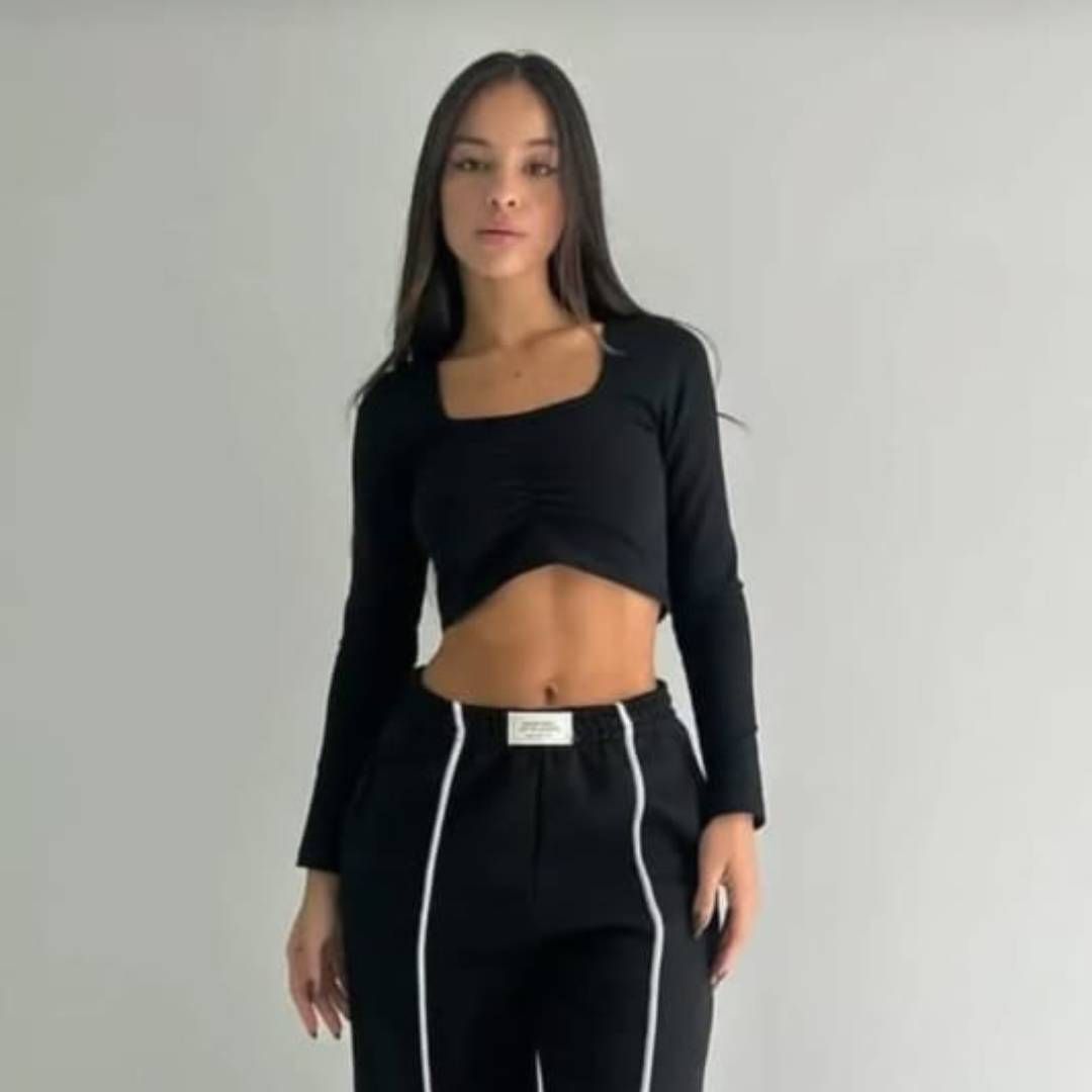 Una mujer lleva un top negro y pantalones negros.