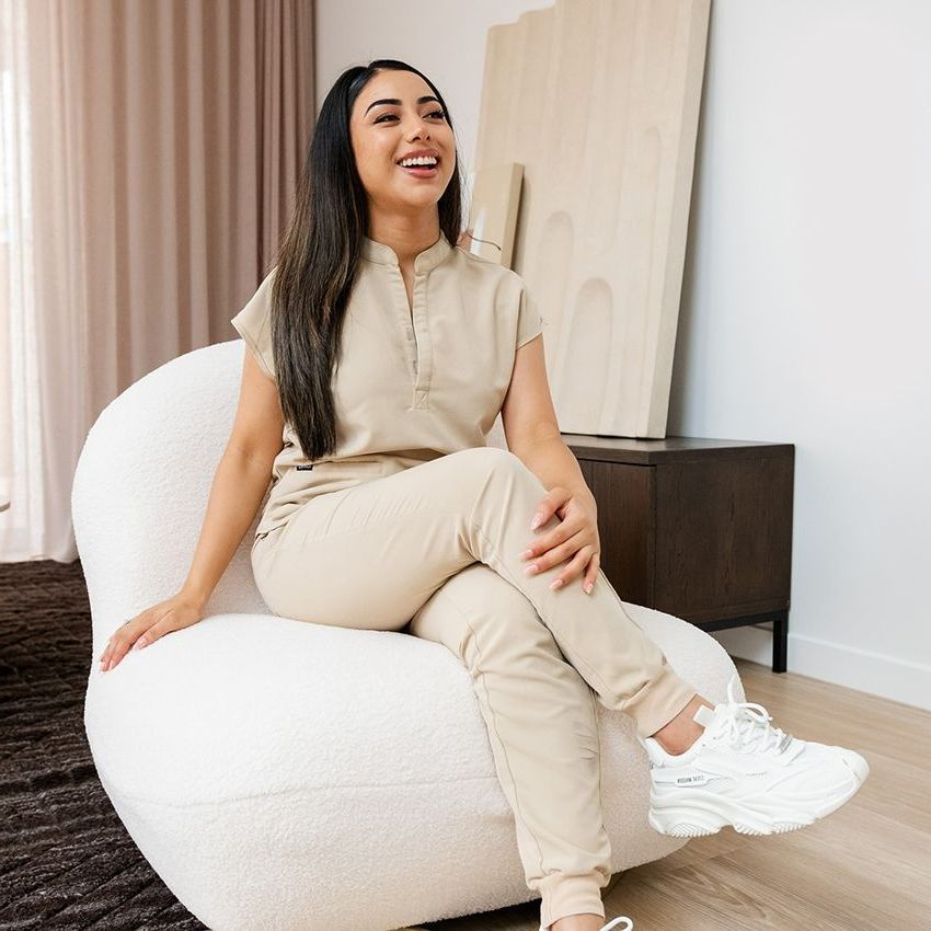 A Woman is Sitting in a Chair With Her Legs Crossed and Smiling — SKN Gold Coast in Southport, QLD