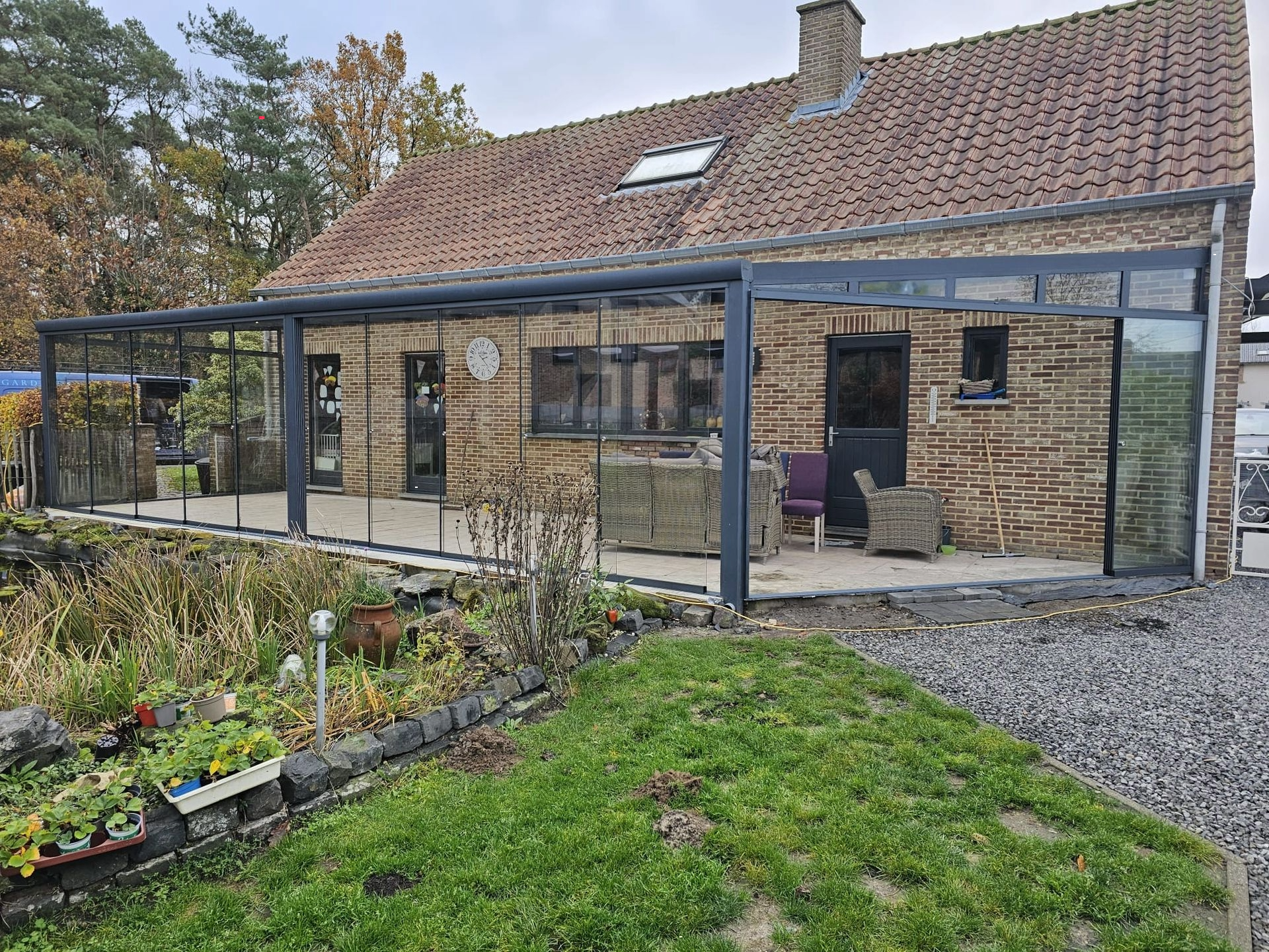Een bakstenen huis met een met glas overdekt terras ervoor.