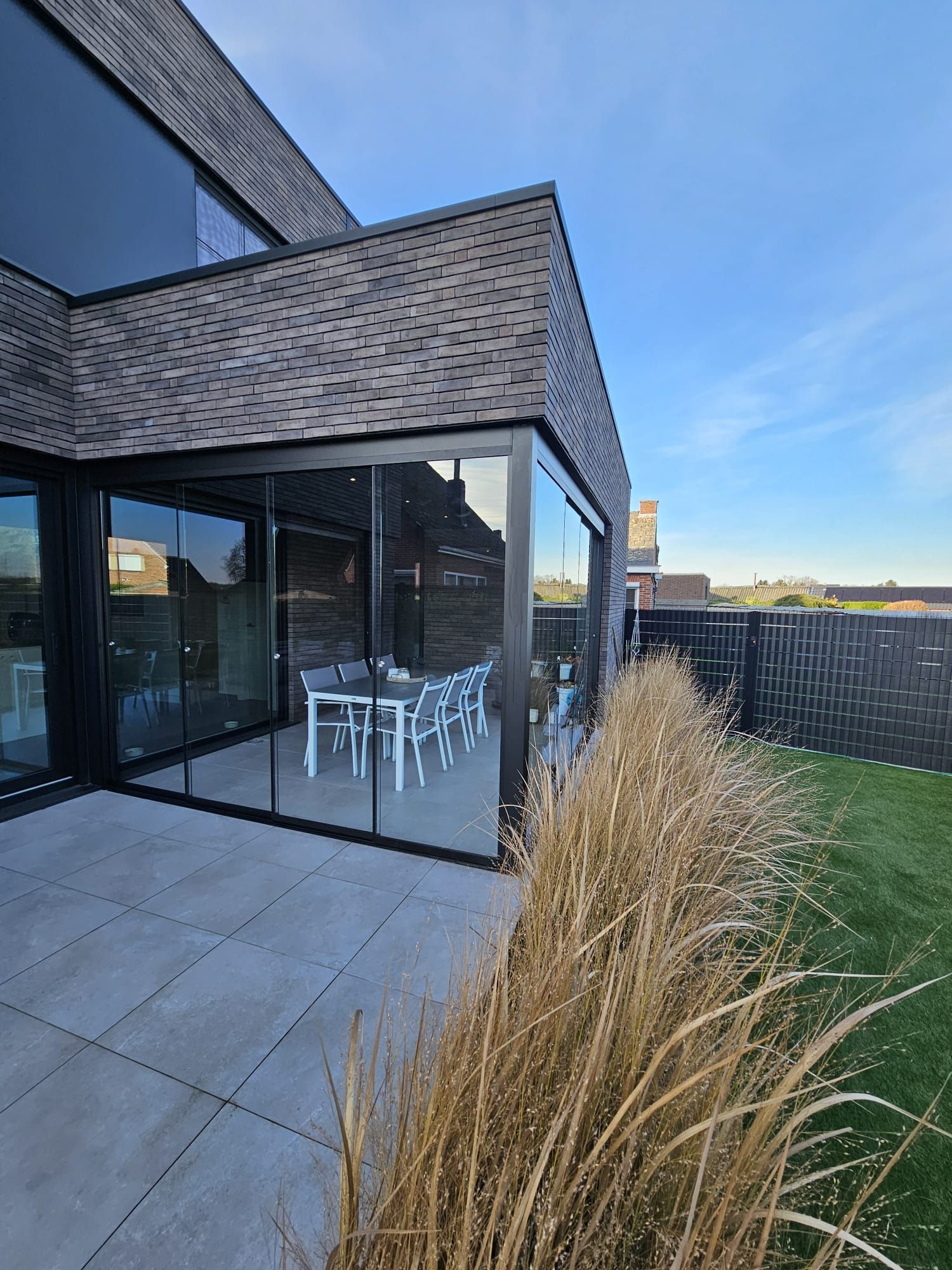 Een groot huis met een terras en glazen schuifdeuren.