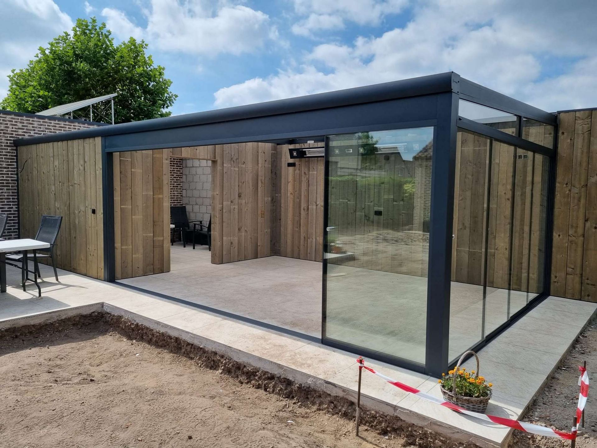Een huis met glazen schuifdeuren en een houten hek.