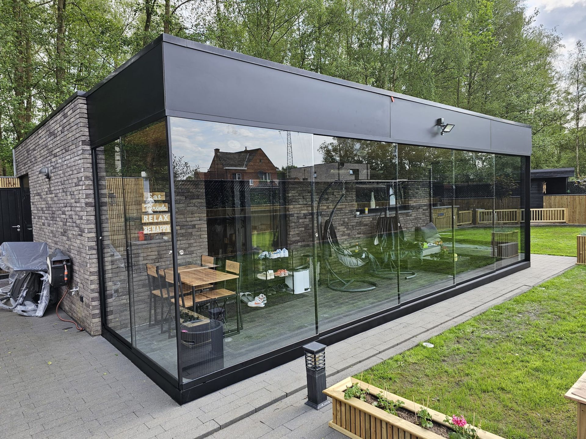 Een groot glazen gebouw met een bakstenen muur en veel ramen.