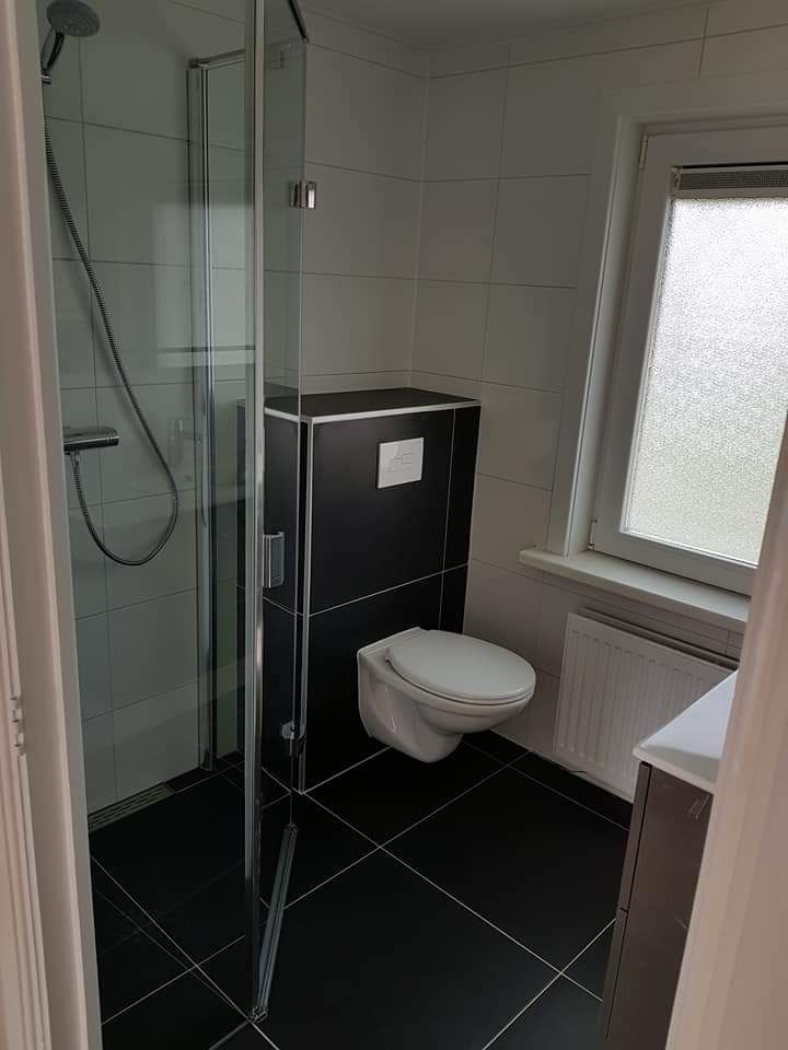 Een huis met glazen schuifdeuren en een houten hek.