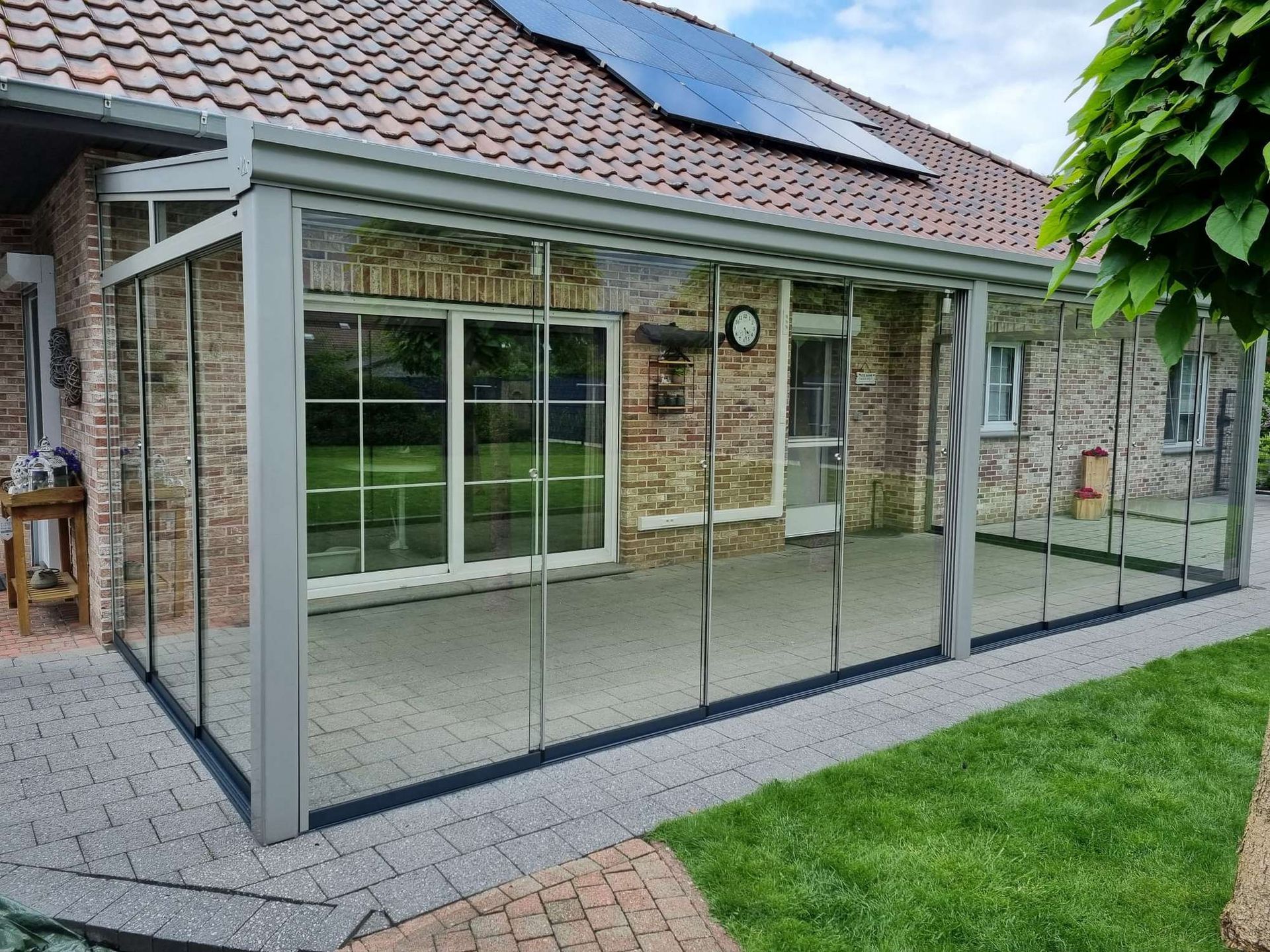 Een bakstenen huis met een glazen veranda en glazen schuifdeuren.