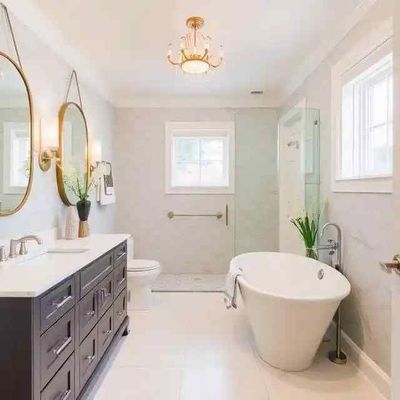 Elegant bathroom with a freestanding tub, double vanity with dark cabinets, and gold accents.