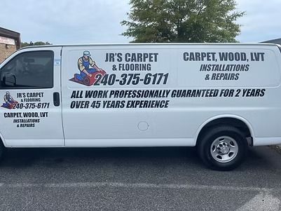 White work van with JR'S CARPET & FLOORING logo, phone number, and services: carpet, wood, LVT, installation & repair.