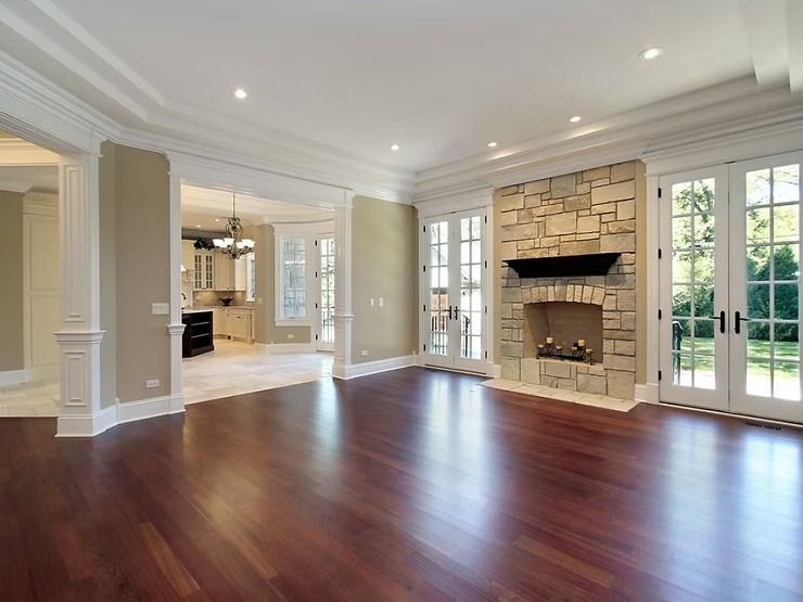Empty living room with hardwood floors, stone fireplace, and French doors.