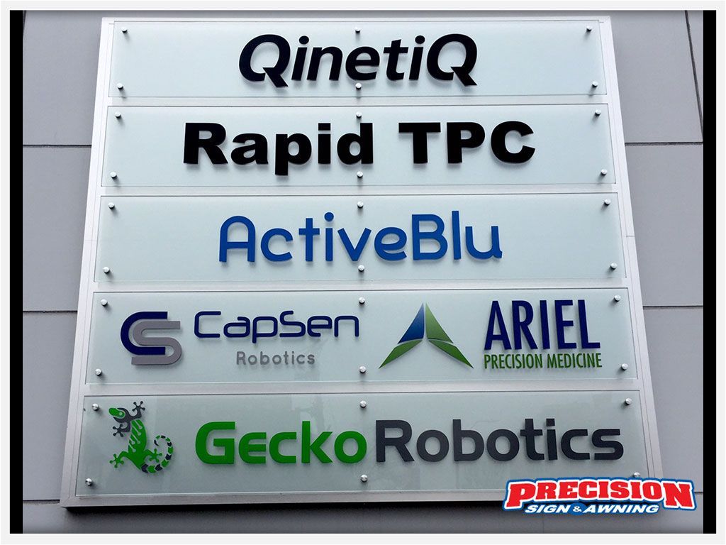 Sign displaying company names: QinetiQ, Rapid TPC, ActiveBlu, CapSen Robotics, ARIEL Precision Medicine, and Gecko Robotics.
