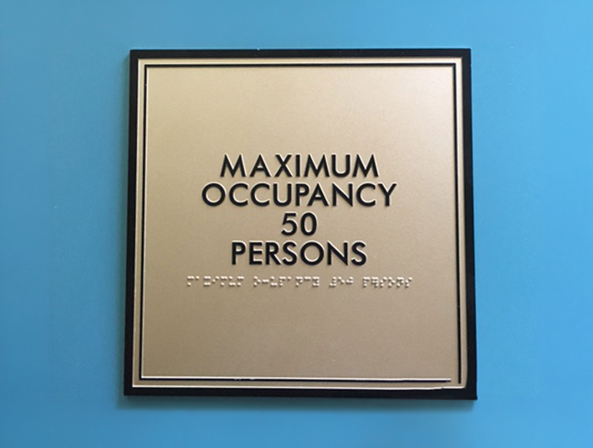 Sign on a blue wall indicating maximum occupancy: