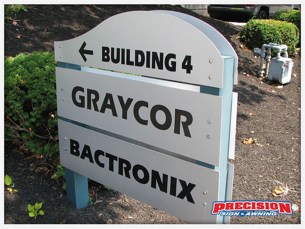 Sign for Building 4, Graycor, and Bactronix, on a silver sign with a blue border, outdoors.