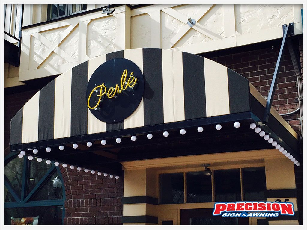 Perbi's restaurant exterior with striped awning, black and cream. Neon sign in a black circle.