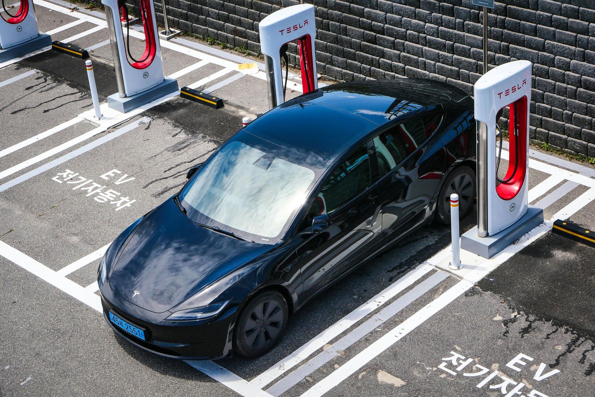 Black Tesla electric car charging at a Supercharger station.