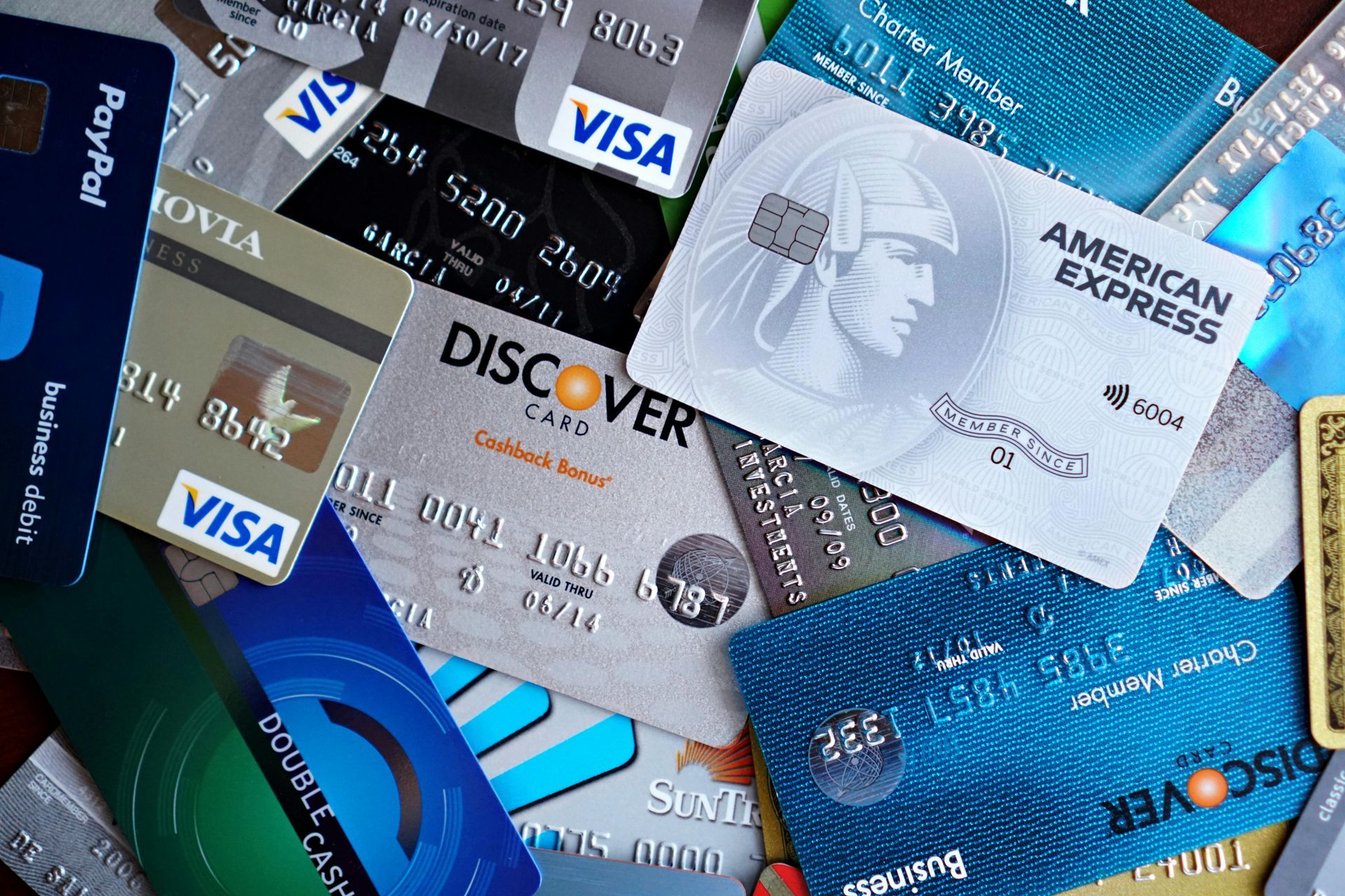 Pile of various credit cards, including Visa, American Express, and Discover.