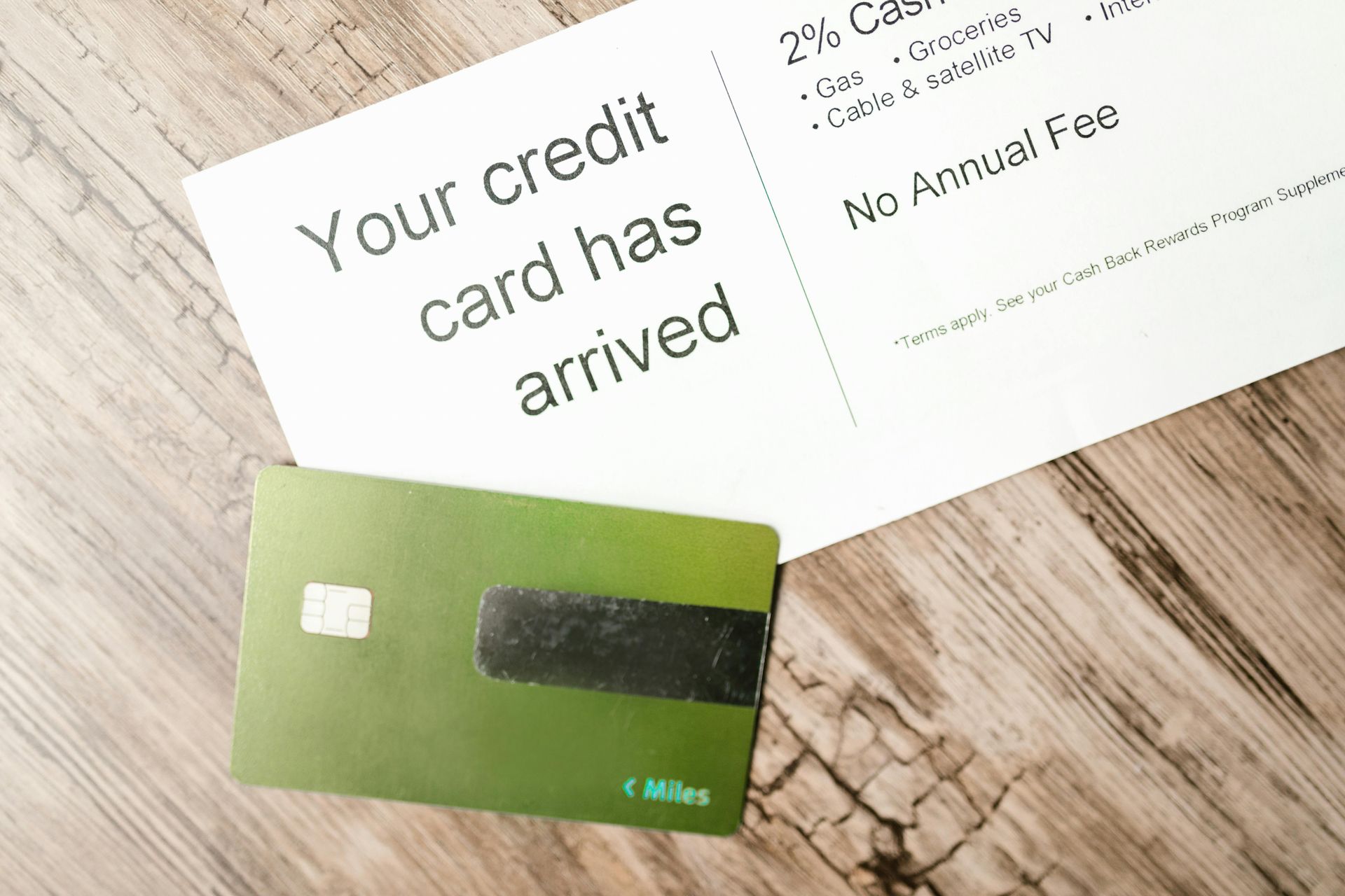 Green credit card and letter on a wooden surface; letter reads, 
